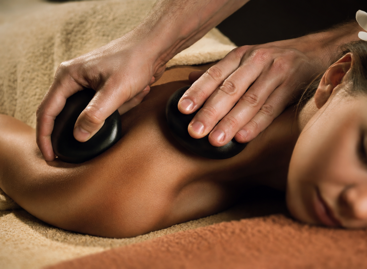 Massage therapist providing a warm hot-stone treatment for relaxation and stress relief